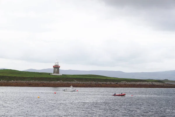 一些小船停泊在海与一座塔在土地在背景 — 图库照片