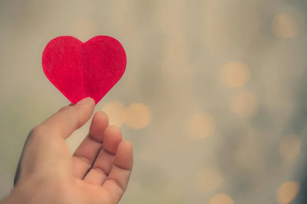 Hartvormige papieren handgreep op bokeh achtergrond., Valentijnsdag — Stockfoto