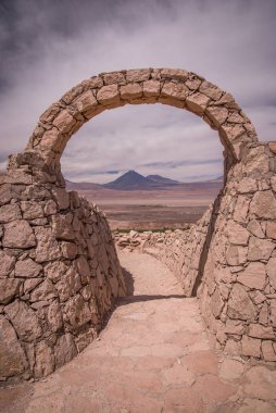 Stone gate at Pukara de Quitor - Inca fortress at Atacama desert with the view at Licancabur volcano in Andes, San Pedro de Atacama, Chile clipart
