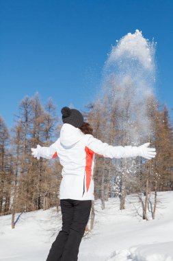 Kar ile oynayan ve mavi Kayak ve arka planda ağaçları ile kış günü açık havada eğleniyor kız