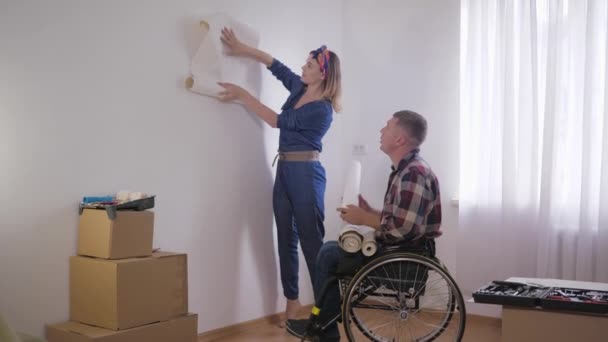 Счастливая пара инвалид мужчина в инвалидной коляске с молодой красивой женщиной выбирает новый интерьер в спальне — стоковое видео
