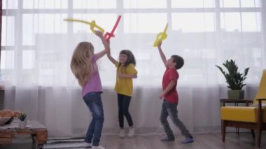 Çocuk partisinde aktif oyunlar, mutlu arkadaşlar balonlarla kavga ederek, zıplayarak ve gülerek eğleniyorlar.