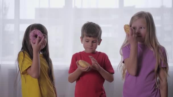 Беззаботное детство, счастливые дети с одним глазом смотреть через пончики, веселясь на вечеринке друзей — стоковое видео