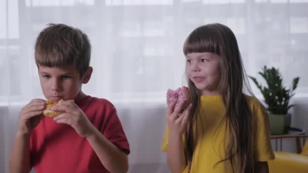 婴儿食品，可爱的孩子们吃着最好的面包店里最受欢迎的甜甜圈后，在睡衣派对上活跃的游戏 — 图库视频影像