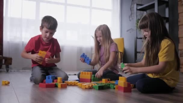 Χαρούμενα παιδιά παίζουν εκπαιδευτικά παιχνίδια, οικοδομήσουμε παιχνίδια από χρωματιστά μπλοκ του σχεδιαστή — Αρχείο Βίντεο