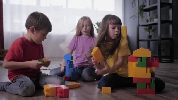 Beziehung der Kinder, charmante Freundinnen und ein netter Junge spielen zusammen pädagogisches Spielzeug mit bunten Blöcken während der Kinderparty — Stockvideo