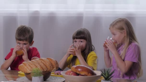 Солодкий стіл, смішні діти кусають і п'ють сік після активних ігор для святкування дитячої вечірки — стокове відео