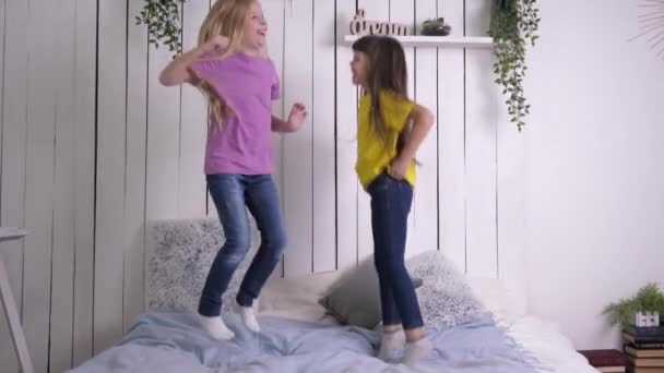 Enfance heureuse et de loisirs, les petites amies s'amusent à sauter sur le lit au ralenti tout en se relaxant à la maison — Video