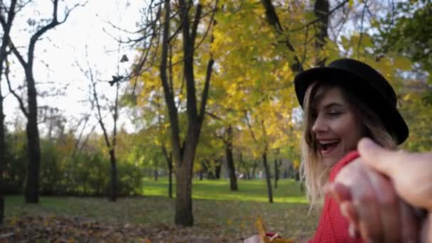 Весела жінка біжить в осінньому парку з букетом жовтого листя в осінній сезон в теплий сонячний день під час заходу сонця — стокове відео