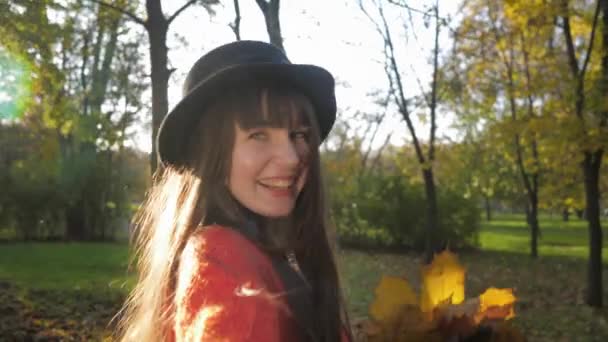 Portret van lachend meisje in hoed met lang haar, ze houdt vriend hand en leidt hem door de herfst park op wandeling tijdens het seizoen van gevallen bladeren — Stockvideo