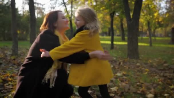 charmante petite fille court rarement dans les bras de sa mère bien-aimée tout en se relaxant dans l'air frais dans un parc d'automne au milieu des feuilles tombées 