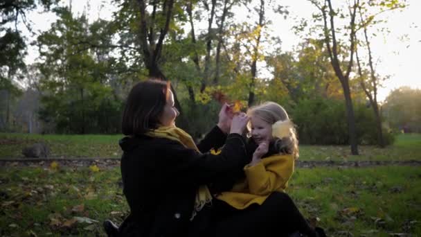 Friendly family, charming mother plays with cute beautiful daughter on lawn in autumn park during fun weekend — Stock Video