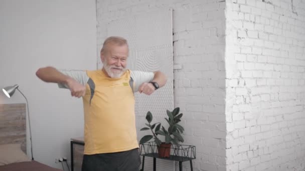 Glad morfar idrottsman leder en aktiv och hälsosam livsstil gör användbara övningar för att upprätthålla vitalitet i sitt rum med kreativ inredning — Stockvideo