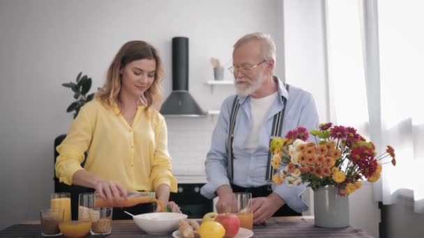 Familj relationer, glad leende barnbarn har kul med sin farfar i glasögon för syn och skägg, älskare av rätt kost, förbereder en hälsosam frukost i köket — Stockvideo