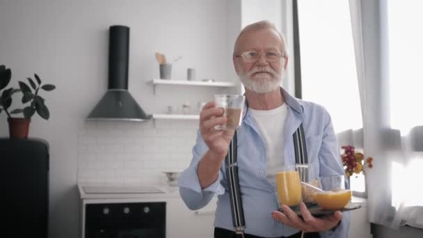 Retrato de un atractivo anciano con barba y gafas para visión, hablando de útiles cereales para mantener la salud — Vídeos de Stock