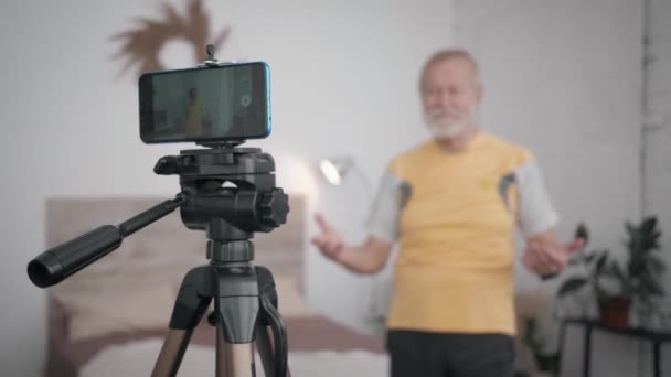 Szociálisan aktív nagyapa Influencers különös figyelmet fordít az egészséges aktív életmód mutatja gyakorlatok az előfizető felvétel videó telefonon blog — Stock videók