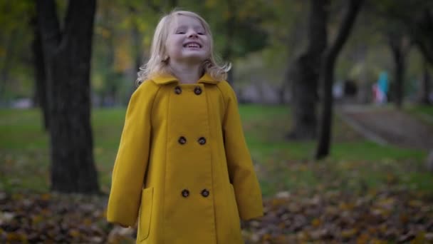 Alegre infancia, retrato de una linda chica divertirse en el parque de otoño mientras se relaja al aire libre — Vídeos de Stock