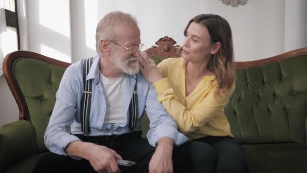 Idős szülők, boldog fiatal lány és szerető idős nagyapa szórakozni aranyos csevegés és nevetés, miközben ül a kanapén a családi hétvégén — Stock videók