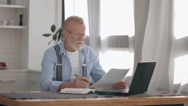 现代退休人员会计自由职业者一边在笔记本电脑上做日常工作，一边在遥远的工作岗位上整理帐目 — 图库视频影像