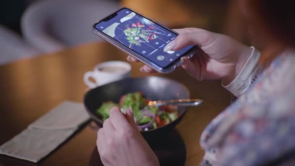 Food-Fotograf, Mode-Blogger fotografiert Gemüsesalat auf Smartphone für seinen Social-Media-Account, während er am Tisch im angesagten Café sitzt — Stockvideo