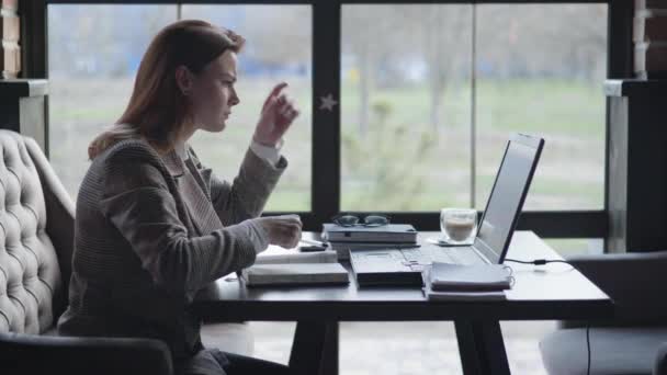 Problems in business, young sad business woman is upset because of problems and poor financial reporting, fists on table and closes laptop cover while working remotely with online bookkeeping while — Stock Video