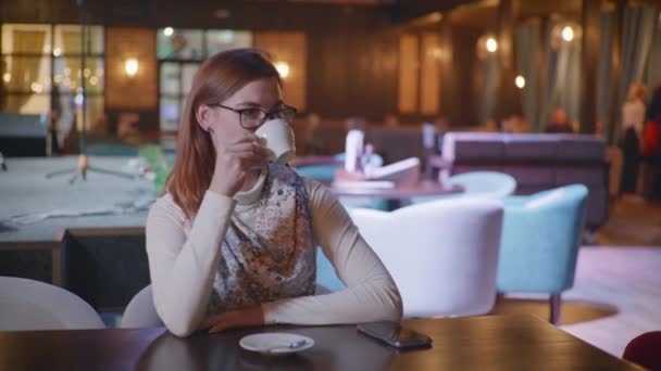 Kaffepaus, attraktiv leende kvinna i glasögon njuter av avkopplande i café, dricker gott kaffe och tittar på kameran när du sitter vid bordet i trendig restaurang — Stockvideo