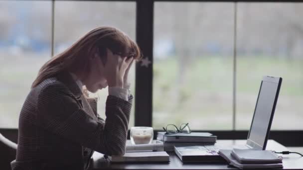 Portret van een vermoeid meisje, een zakenvrouw is nerveus vanwege hard werken online zitten aan tafel door raam in een duur restaurant tijdens de koffiepauze — Stockvideo