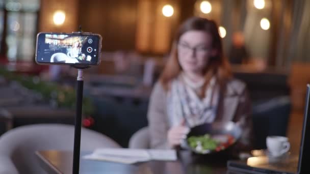 Populaire blogger schrijft vlog inhoud op de juiste voeding op mobiele telefoon vertelt hoe om gewicht te verliezen en modieuze dieet zitten aan tafel in luxe restaurant — Stockvideo