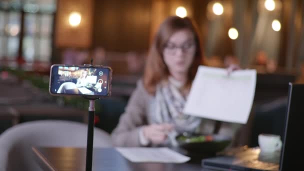 Cibo sano, una giovane bella blogger parla di una dieta alla moda, scrive video per il suo vlog su uno smartphone seduto a tavola in caffè, persone e blog — Video Stock