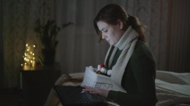 Tıbbi ilaçlar, boğazında eşarp olan viral hastalığı olan bir kız internette yatakta otururken kullandığı ilaçların tarifini arıyor.