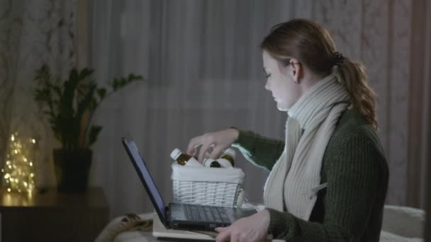 Behandeling ziek meisje, jonge vrouw die lijden aan virale ziekte of griep meet de temperatuur met thermometer zit met laptop en bestelt medicijnen online — Stockvideo