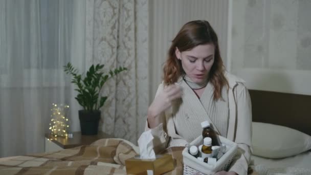 Špatné zdraví, nezdravá žena trpící sezónními chorobami, měří teplotu pomocí teploměru a drží léky v rukou, koncepce onemocnění — Stock video