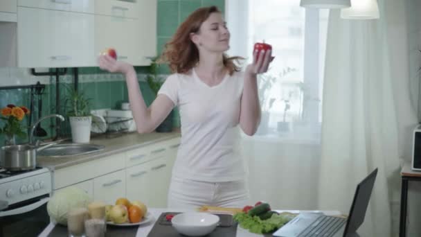 Lachend meisje gelukkig na succesvolle dieet poseren op camera met gezond voedsel in de keuken en meet haar taille met tape maatregel — Stockvideo