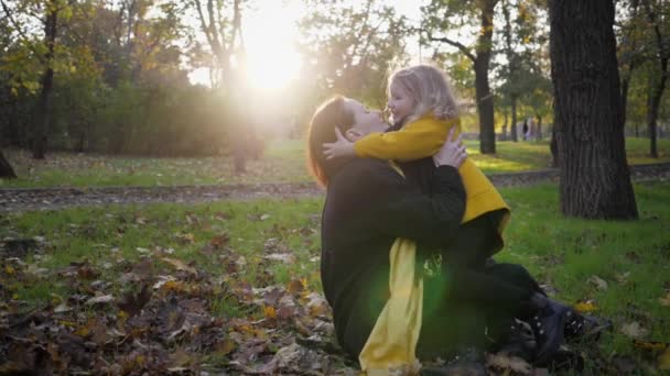 秋の公園若いチャーミングな女の子の娘を持つ魅力的な若い母親は、秋の季節に庭で楽しみを持っています幸福の概念 — ストック動画