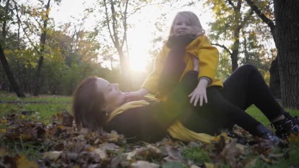 Familj promenad, porträtt av liten charmigt söt flicka med sin attraktiva unga mamma som har kul i höstparken — Stockvideo