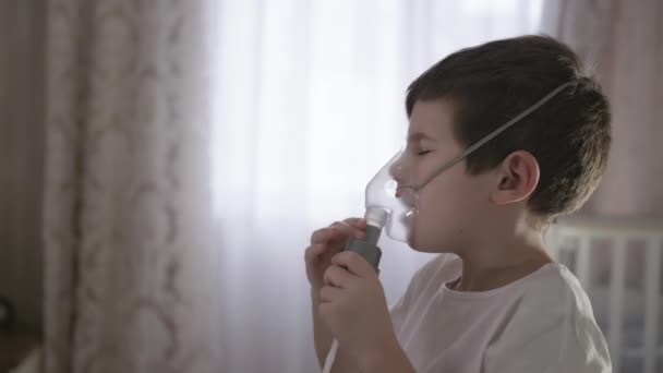 Niño enfermo inhalando a través de la máscara del inhalador en el hogar, trata la inflamación de las vías respiratorias a través del nebulizador para prevenir la secreción nasal, tos, gripe — Vídeos de Stock