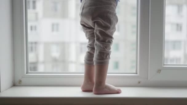 Livsfara, barns fötter på fönsterbrädan, liten pojke i fara stående nära fönstret — Stockvideo