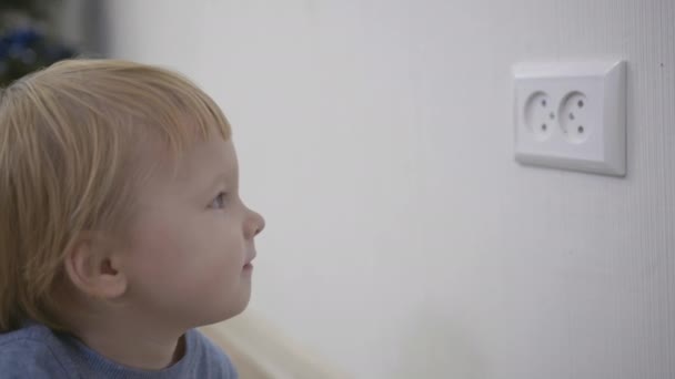 Nyfikna barn är i fara, liten pojke försöker sätta ett finger i eluttaget närbild hemma — Stockvideo