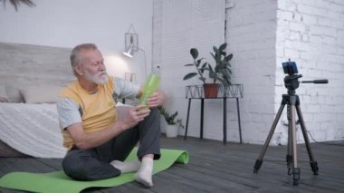 Eski blogcu, yaşlı adam nüfuzlu kişiler sporu seviyor. Akıllı telefondan, yaratıcı iç mekanlarda yoga minderinde otururken abonelere su önerilmesi için bir içki eleştirisi alıyor.