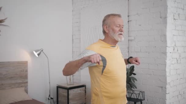 Γέρος όμορφος άντρας οδηγεί έναν υγιεινό τρόπο ζωής και κάνει χρήσιμες ασκήσεις για την υγεία και τη ζωτικότητα στο δωμάτιο με ένα δημιουργικό εσωτερικό — Αρχείο Βίντεο