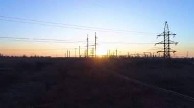 Elektrik ve çevre problemi, güzel turuncu gün batımı altında yüksek voltaj kulelerinin ve elektrik hatlarının hava görüntüsü