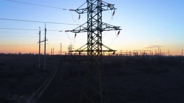 Eficiência energética, voando para cima torre de eletricidade de alta tensão e linhas de energia ao pôr do sol acima do campo — Vídeo de Stock