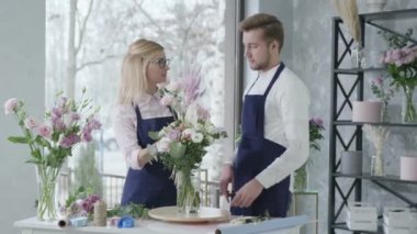Çiçekçiler, mutlu çalışanlar çiçekçide çalışan genç adam ve kadın güzel çiçeklerden oluşan bir buket, takım çalışması