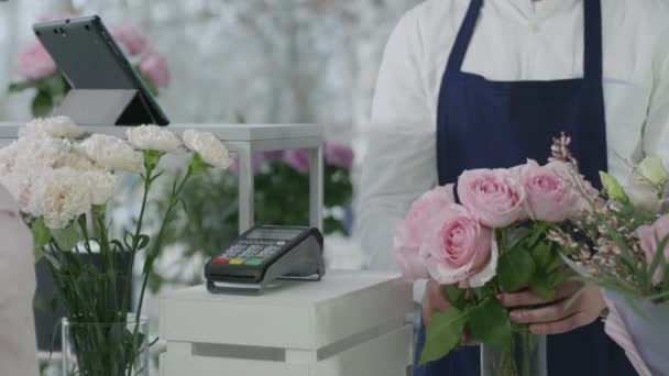 Kontaktlös betalning, betalar nöjd köpare bukett blommor i modern blomsterbutik vid kassan terminal med hjälp av smartphone, framgångsrika små företag — Stockvideo