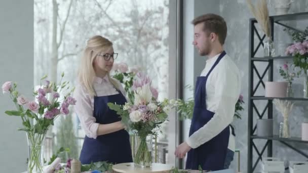 Співпраця співробітників, творча команда жіночих і чоловічих флористів, власники малого бізнесу працюють над створенням букета красивих квітів в успішному квітковому магазині — стокове відео