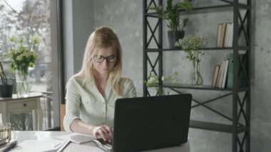 Başarılı bir girişim, genç mutlu kız girişimci küçük işletme sahibi çiçekçide dizüstü bilgisayarda çalışıyor ve internetten buketlerin teslimatını kontrol ediyor.