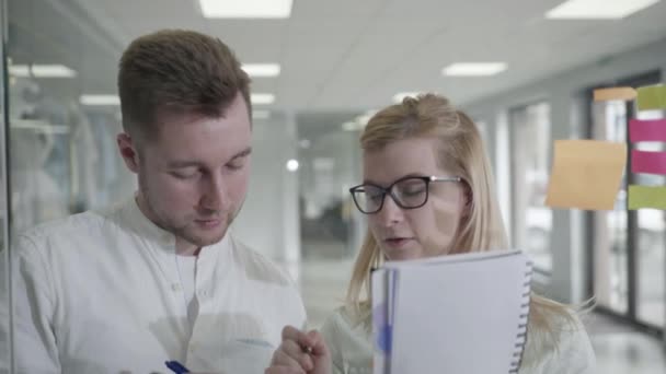 Geschäftsplanung, Mann und Frau mit klebrigen Zetteln auf Glas Whiteboard Brainstorming Supervisor Frau arbeitet mit Kollegen zeigt Problemlösungsstrategie in Büro-Meeting — Stockvideo