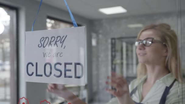 Pequeña empresa, gerente feliz hembra en gafas para cambiar la visión cerrado para abrir signo en la ventana sonriendo mirando fuera esperando a los clientes, puesta en marcha — Vídeos de Stock