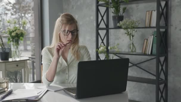 Retrato de una joven empresaria, propietarios de pequeñas empresas que trabajan con un ordenador portátil en una oficina, mirando el monitor digital y anotando ideas creativas para una empresa en un cuaderno — Vídeo de stock