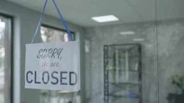 beginning of work day, attractive male entrepreneur is changing door plate from sorry we are closed to yes we are open, business concept